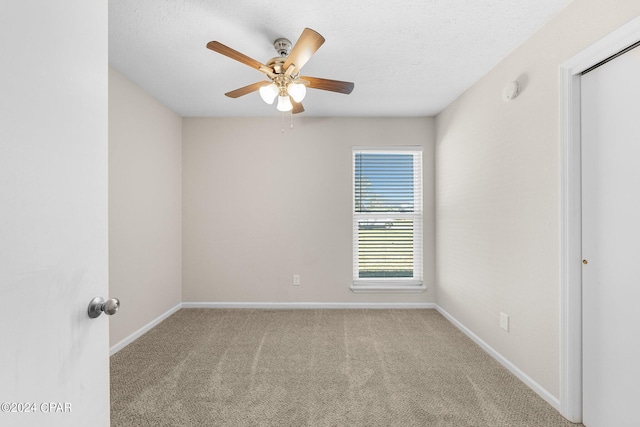 carpeted empty room with ceiling fan and a textured ceiling