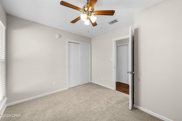 unfurnished bedroom with ceiling fan, a textured ceiling, light carpet, and a closet