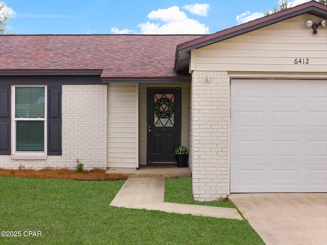 view of exterior entry with a lawn and a garage