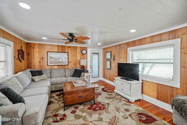 living room with light hardwood / wood-style floors, a wealth of natural light, and wood walls