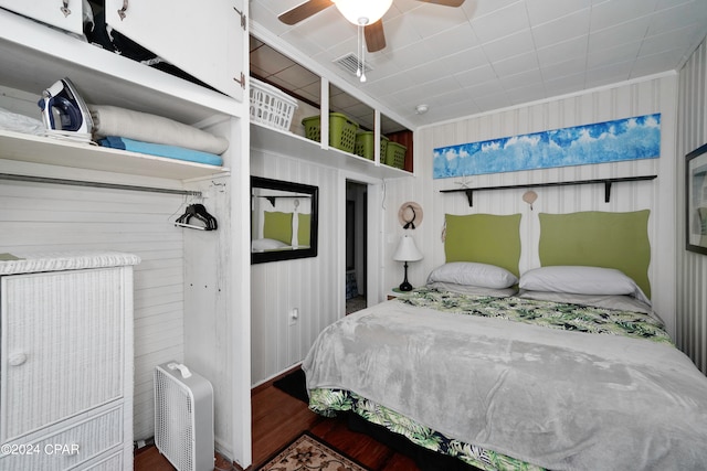 bedroom featuring ceiling fan, wooden walls, and wood-type flooring