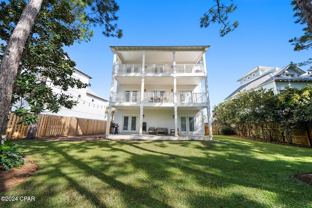 back of property featuring french doors, a balcony, and a yard