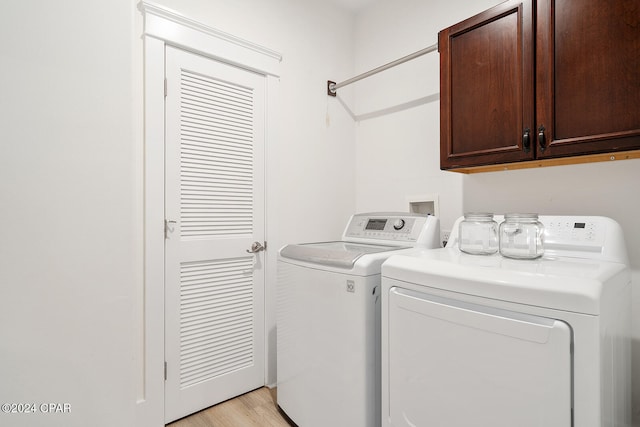 clothes washing area featuring light wood-type flooring, cabinets, and washing machine and clothes dryer