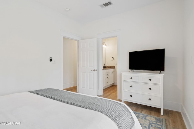 bedroom with light wood-type flooring and ensuite bathroom