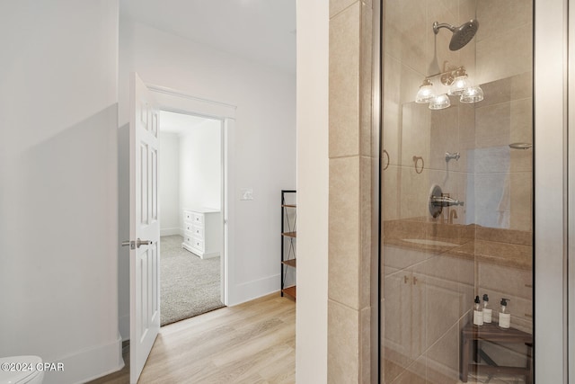 bathroom with hardwood / wood-style floors and a shower with shower door