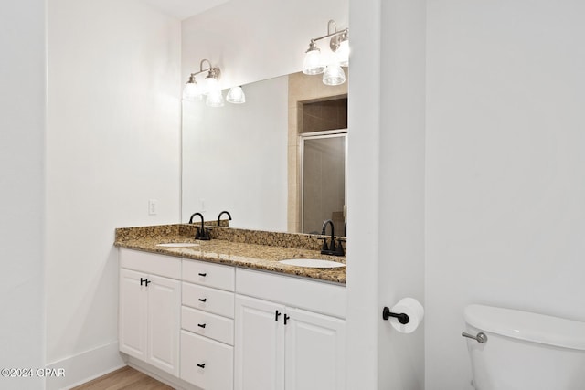 bathroom with toilet, vanity, hardwood / wood-style floors, and a shower with shower door