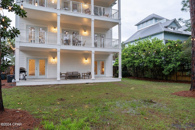 back of house with a lawn, outdoor lounge area, and french doors