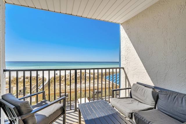 balcony with a water view and a view of the beach