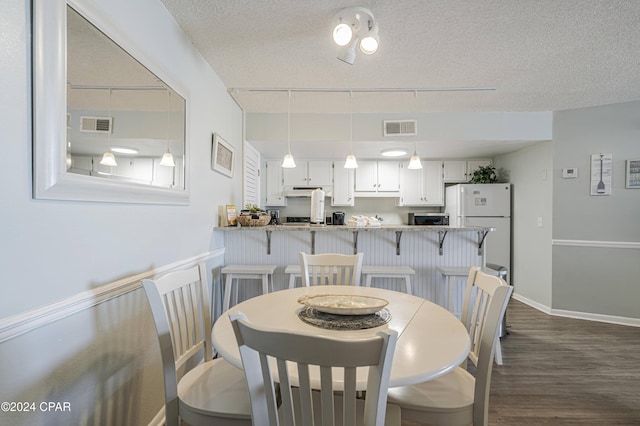 dining space featuring a textured ceiling and dark hardwood / wood-style floors