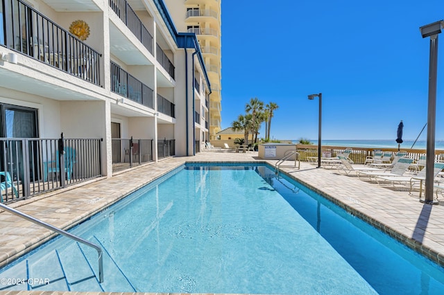 view of swimming pool featuring a water view and a patio