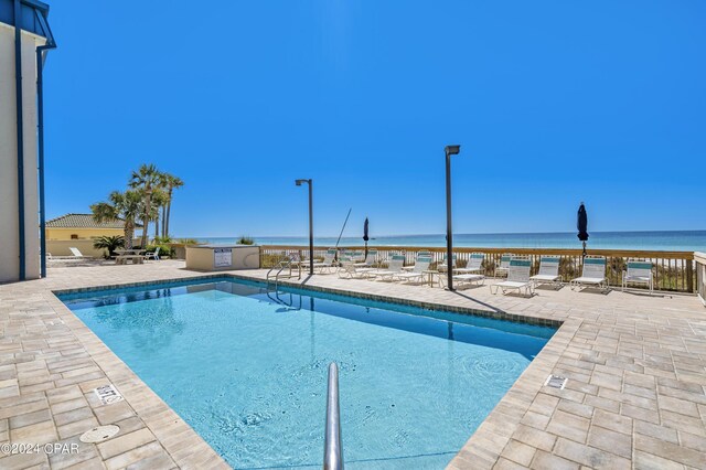 view of swimming pool with a patio, a water view, and exterior kitchen