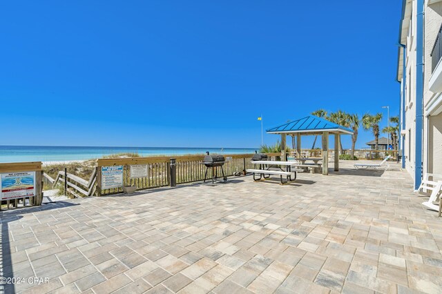 view of patio with a gazebo, a water view, and a view of the beach