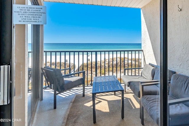 balcony with outdoor lounge area, a water view, and a beach view