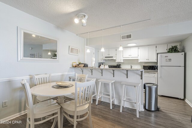 dining space featuring a textured ceiling and dark hardwood / wood-style floors