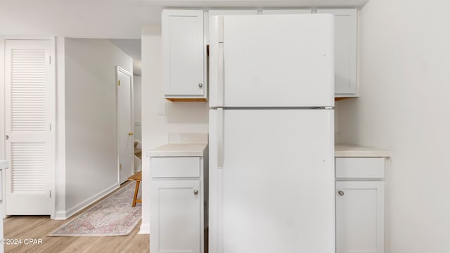 kitchen featuring white cabinets, light hardwood / wood-style flooring, and white fridge