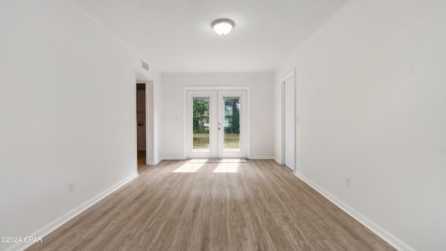 empty room with french doors and light hardwood / wood-style flooring