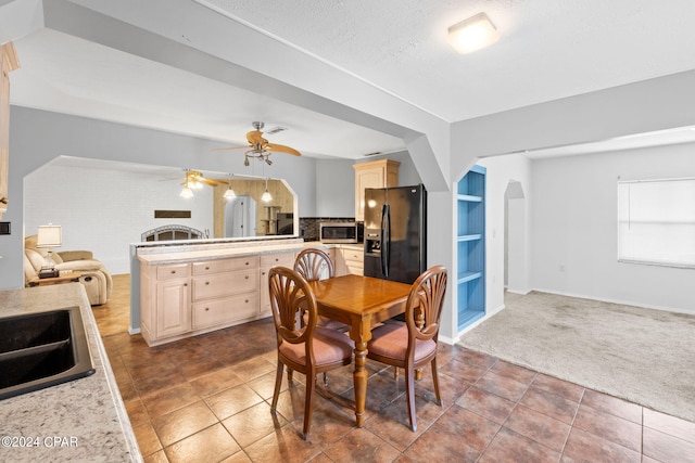 dining area featuring tile patterned floors, built in shelves, arched walkways, carpet floors, and a ceiling fan