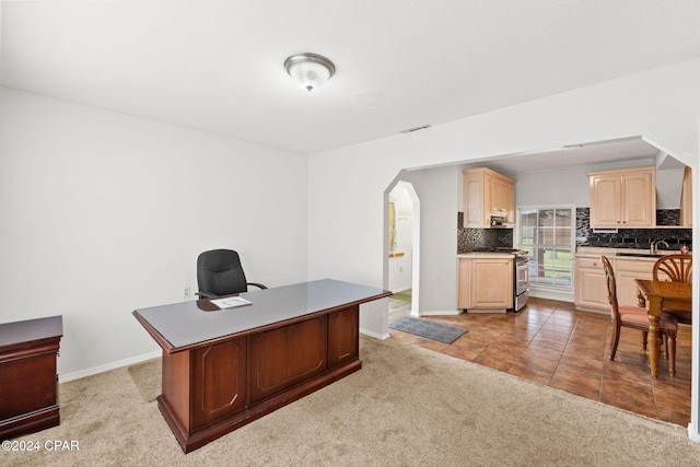office with baseboards, visible vents, a sink, arched walkways, and light carpet