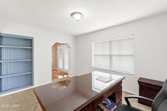 carpeted office featuring baseboards, arched walkways, and built in shelves