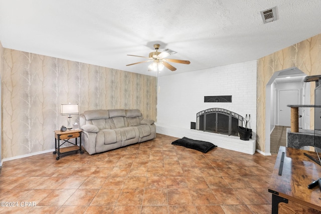 living room featuring a ceiling fan, a brick fireplace, visible vents, and wallpapered walls