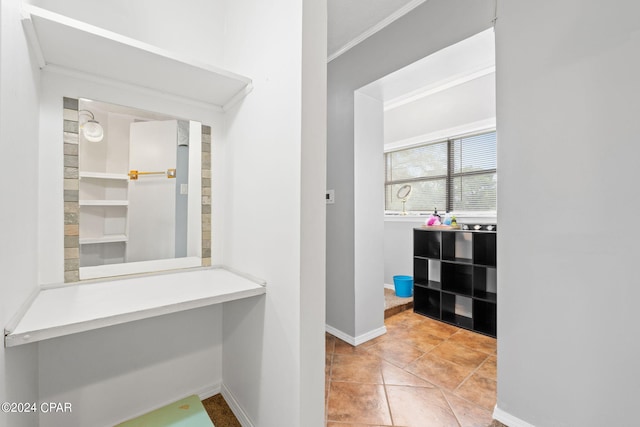 interior space with built in study area, crown molding, baseboards, and tile patterned flooring
