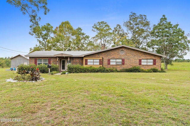 ranch-style home featuring a chimney, brick siding, and a front lawn