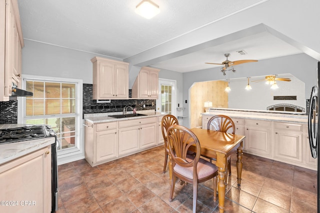 kitchen featuring stainless steel range with gas stovetop, backsplash, ceiling fan, and plenty of natural light