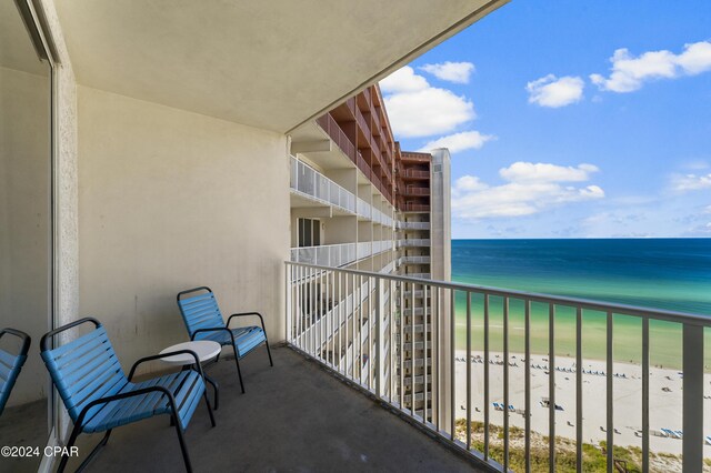 balcony featuring a view of the beach and a water view