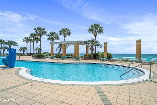 view of pool with a pergola, a patio area, and a water view