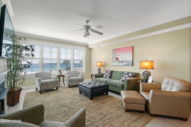 tiled living room with crown molding, a fireplace, a water view, and ceiling fan