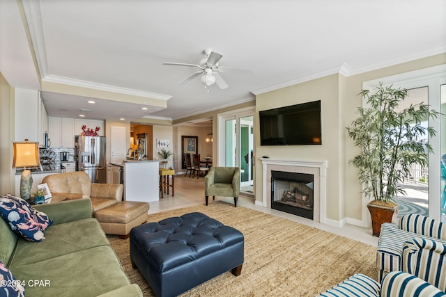 living room with a tile fireplace, ceiling fan, ornamental molding, and light tile patterned flooring