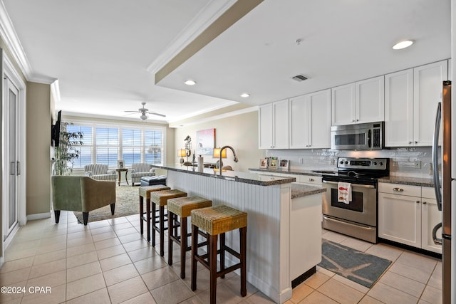 kitchen featuring a center island with sink, white cabinets, and appliances with stainless steel finishes