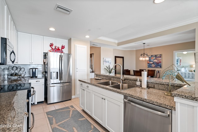 kitchen with stainless steel appliances, white cabinetry, dark stone counters, and sink