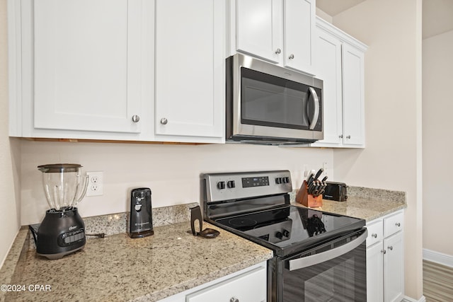 kitchen with white cabinets, light stone countertops, baseboards, and stainless steel appliances