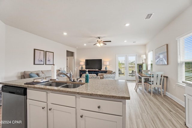 kitchen featuring open floor plan, white cabinets, dishwasher, and a sink