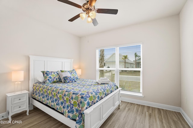 bedroom featuring a ceiling fan, light wood-style flooring, and baseboards