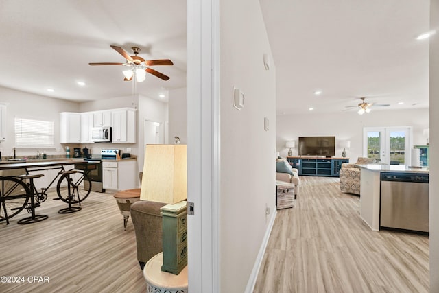 kitchen with stainless steel appliances, a wealth of natural light, open floor plan, and white cabinetry