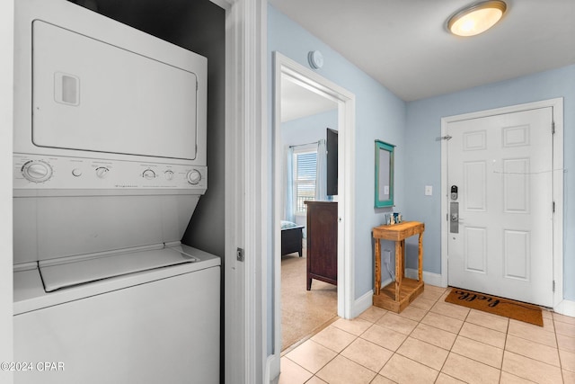 laundry area with stacked washer and dryer and light tile patterned flooring