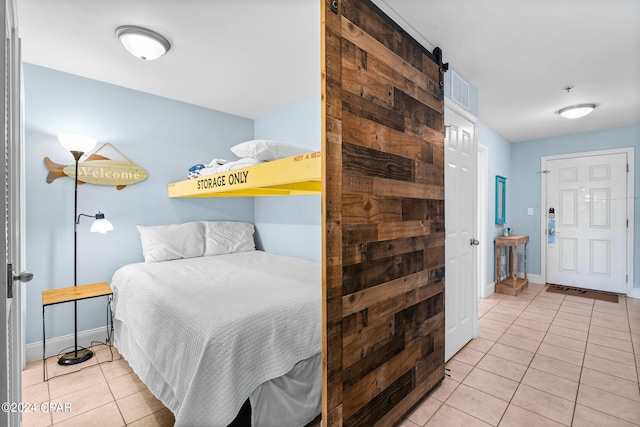 bedroom with a barn door and light tile patterned floors