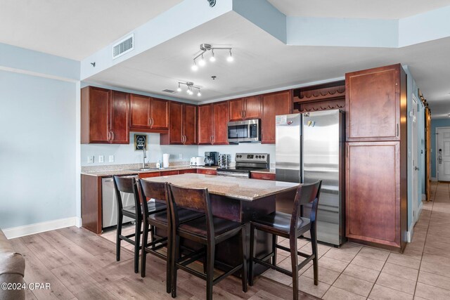 kitchen featuring a breakfast bar area, a barn door, stainless steel appliances, light hardwood / wood-style floors, and a center island