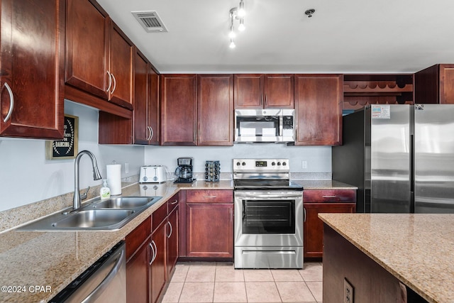 kitchen with light stone counters, light tile patterned flooring, appliances with stainless steel finishes, and sink