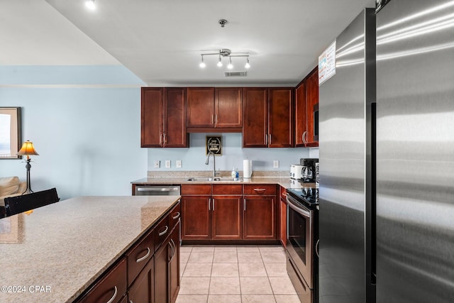 kitchen featuring appliances with stainless steel finishes, sink, light stone counters, and light tile patterned floors