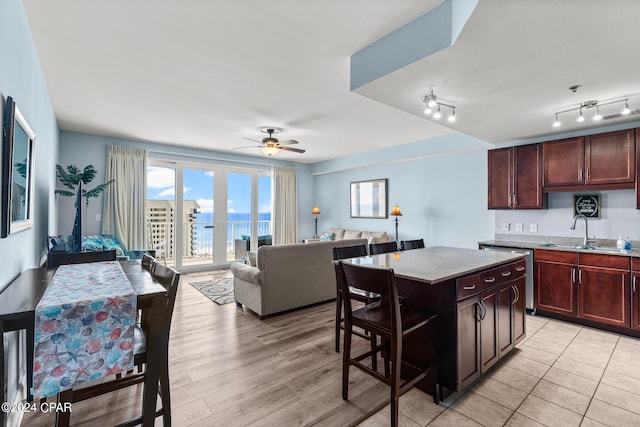 kitchen with ceiling fan, a kitchen island, light wood-type flooring, dishwasher, and sink