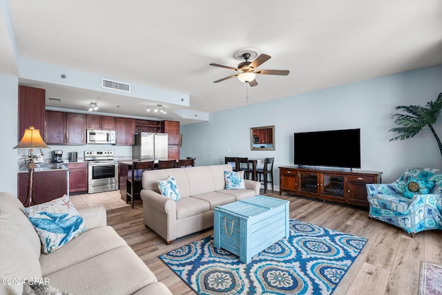 living room with sink, light wood-type flooring, and ceiling fan