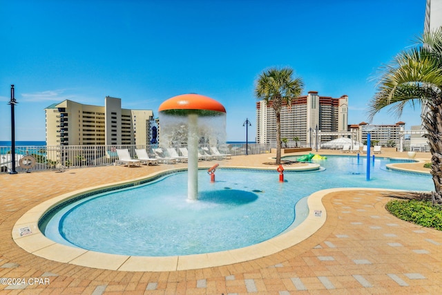 view of swimming pool featuring a water view, pool water feature, and a patio area