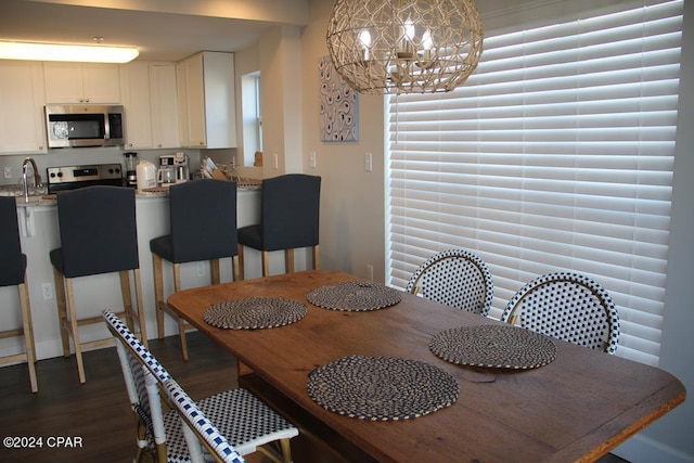 dining space featuring dark hardwood / wood-style flooring, a notable chandelier, and sink