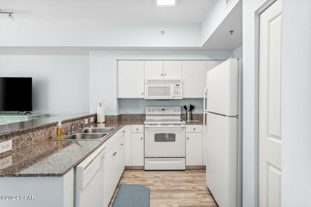 kitchen with sink, white appliances, dark stone countertops, light hardwood / wood-style floors, and white cabinets