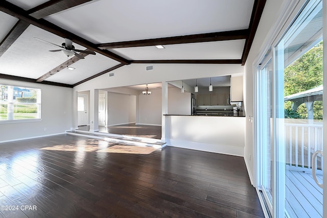 unfurnished living room with lofted ceiling with beams, ceiling fan with notable chandelier, dark wood finished floors, and baseboards