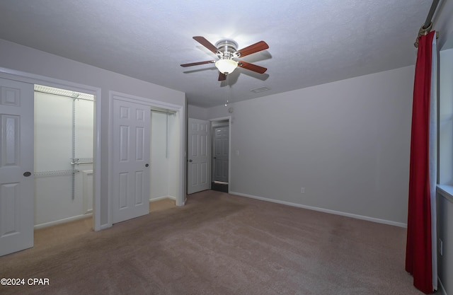 unfurnished bedroom with carpet, visible vents, a textured ceiling, and baseboards