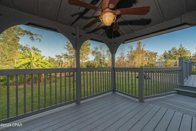 wooden terrace featuring a lawn and a ceiling fan